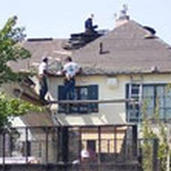 Workers on a roof conducting repairs for General Roofing Company in Oakland, with materials and equipment visible on the rooftop.